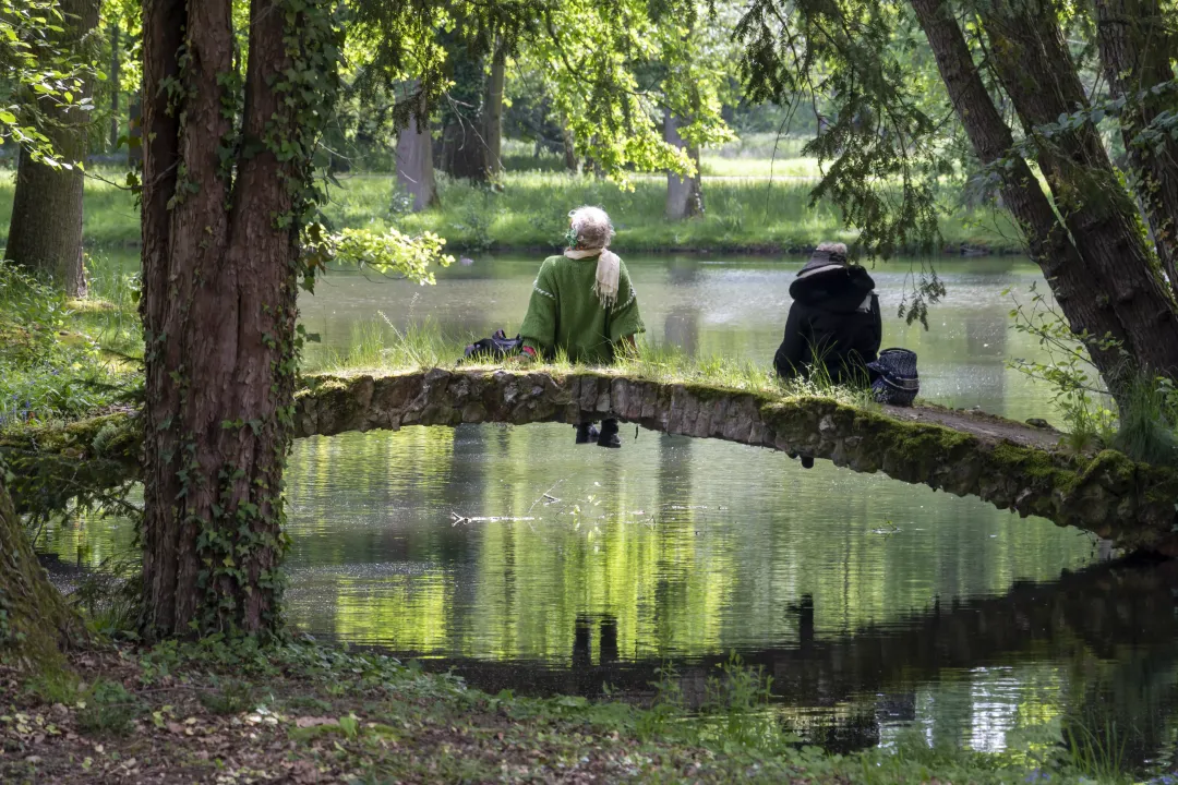 Two people lounging on a bridge overlooking a pond in Schoppenwihr park