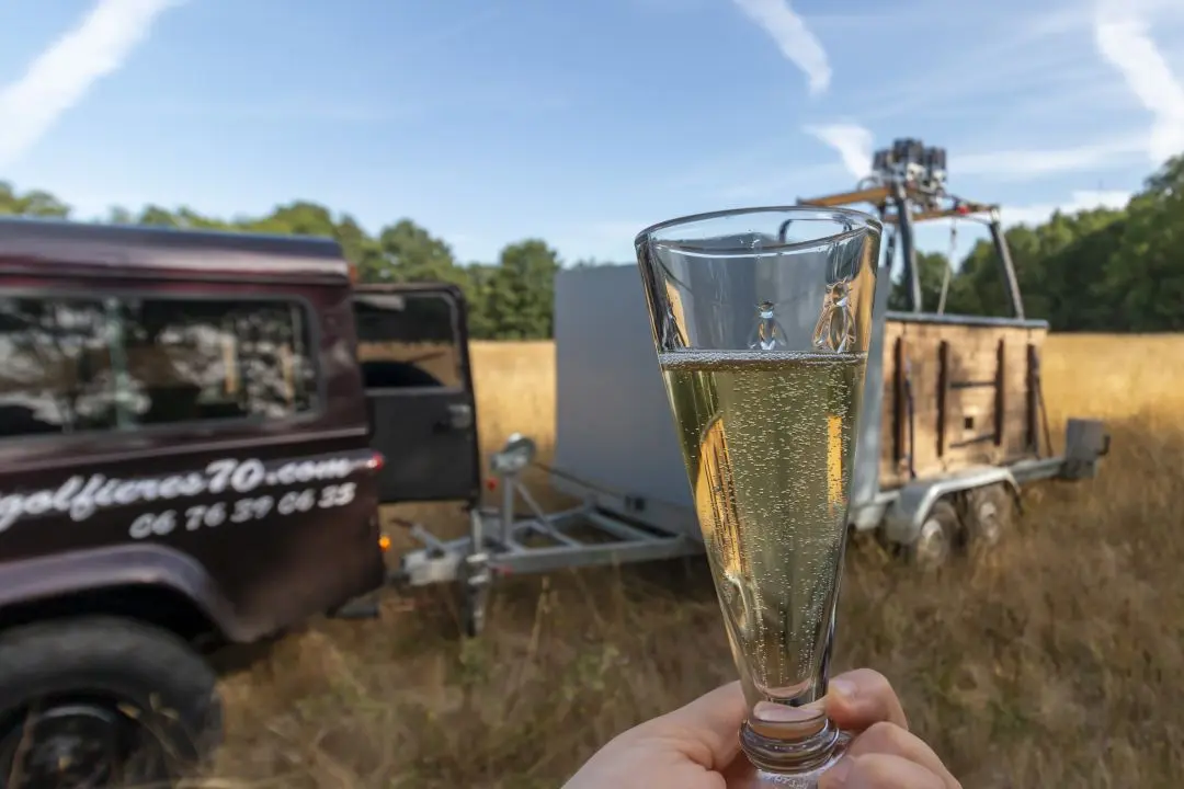 A glass of champagne in front of a hot air balloon basket